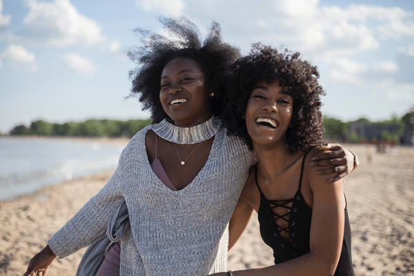 Two people smiling and holding each other on a beach